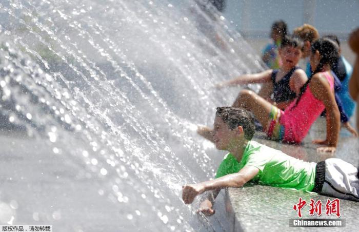 资料图：美国华盛顿，儿童在喷泉池边玩耍消暑。
